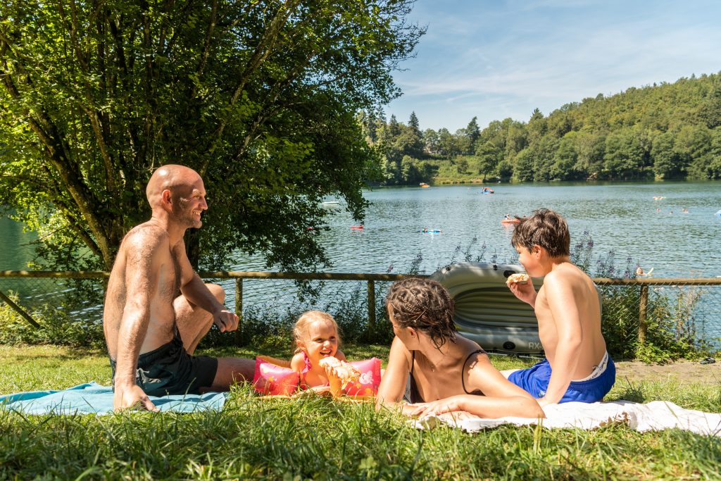 Familie entspannt auf der Liegefläche des Naturfreibades Gemündener Maar