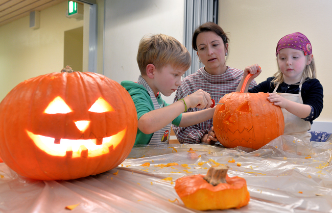 Familie schnitzt Kürbisse beim Halloweenprogramm