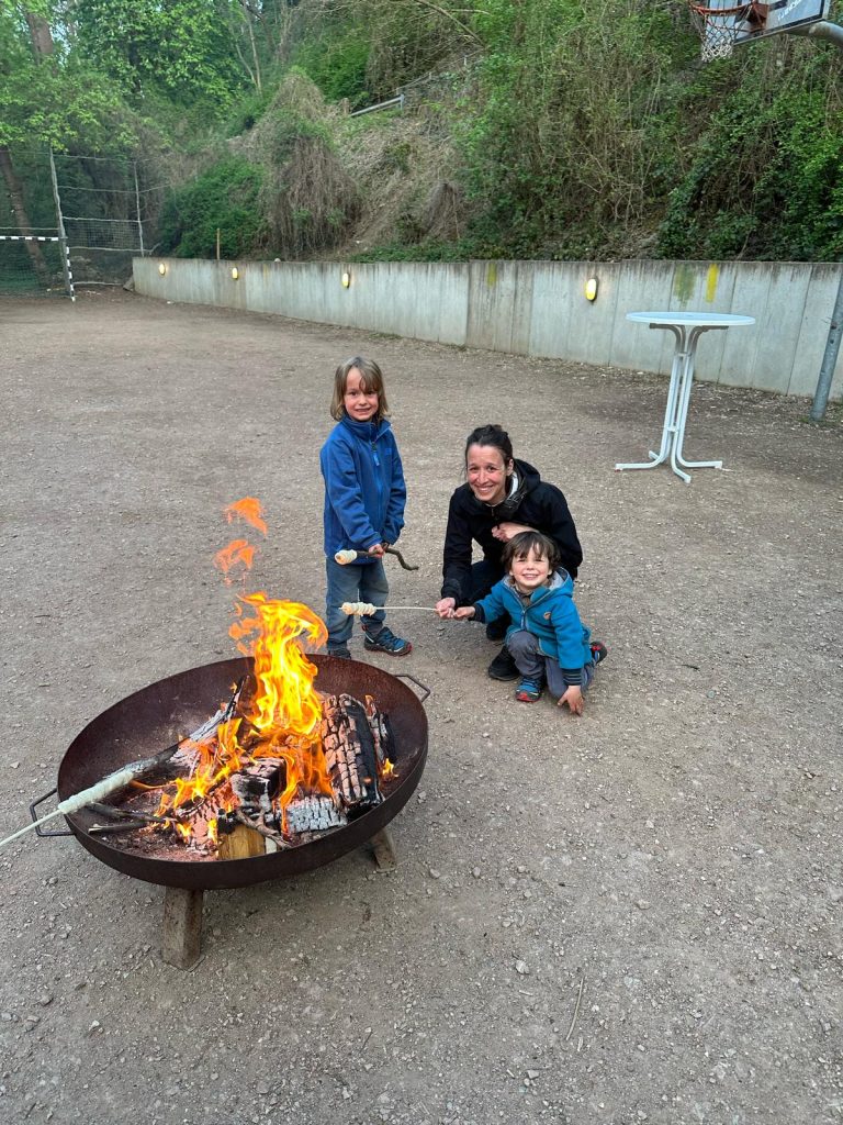 Familie am Feuer backt Stockbrot