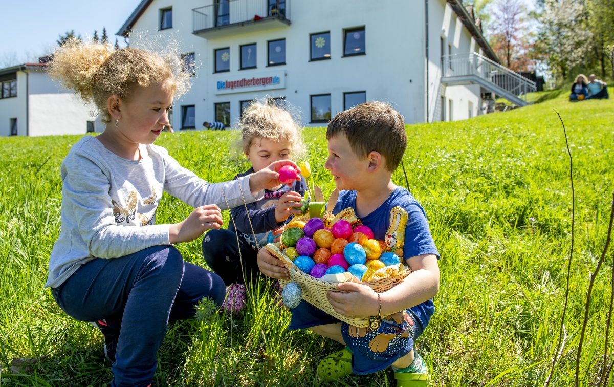 Drei Kinder sammeln bunte Ostereier vor der Jugendherberge Tholey
