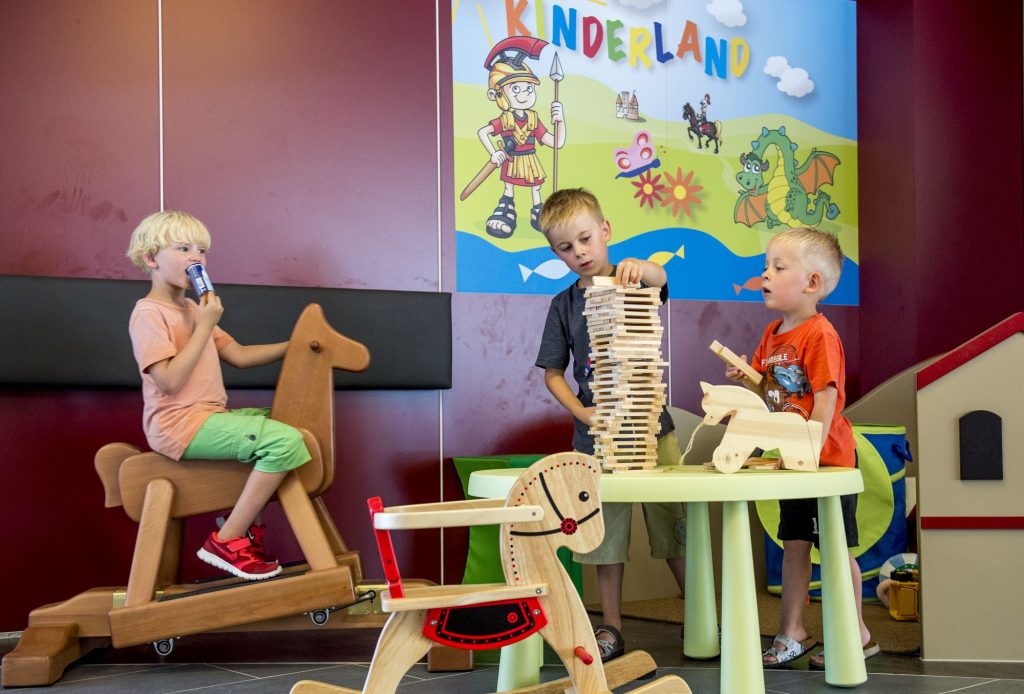 Drei Jungen spielen in der Speilecke mit Bausteinen und Schaukelpferd. 