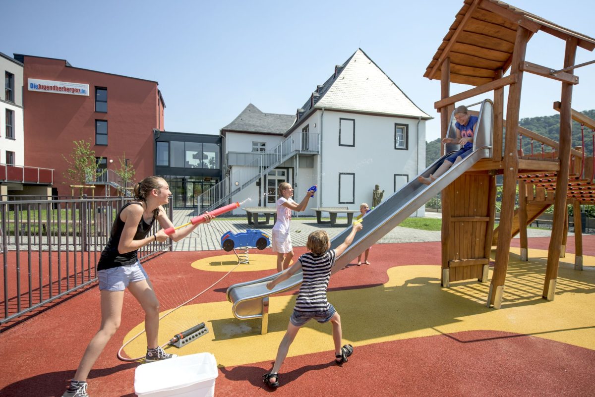 Kinder spielen mit Wasserpistolen auf dem Spielplatz der Jugendherberge Leutesdorf.