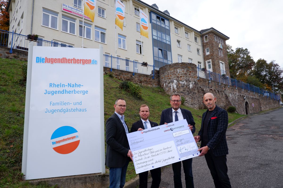 Übergabe eines symbolischen Spendenschecks von Löwen Entertainment an Die Jugendherbergen in Rheinland-Pfalz und im Saarland vor der Rhein-Nahe-Jugendherberge in Bingen