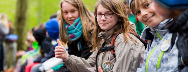 Schüler zeigen Daumen hoch im herbstlichen Wald