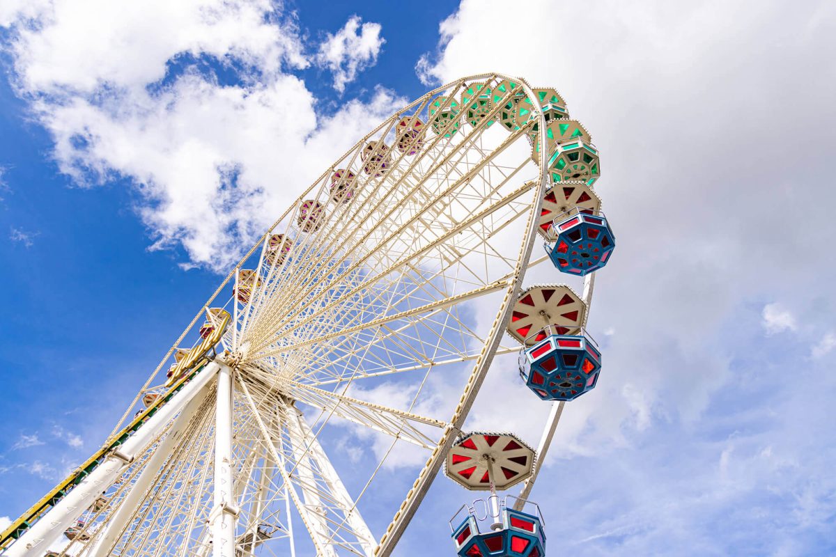Riesenrad vor blauem Himmel mit weißen Wolken