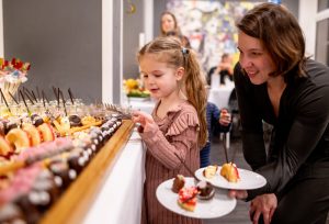 Mutter und Tochter bedienen sich am leckeren beim Büfett zum Familienprogramm Leuchtenden Kinderaugen.