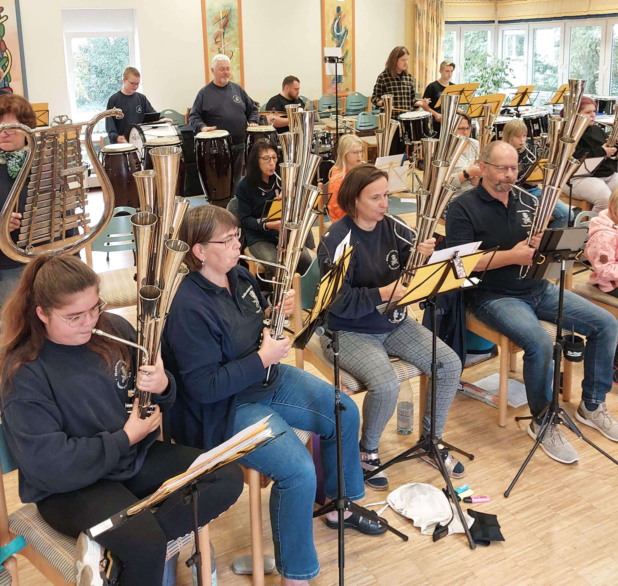 Eine große Musikgruppe mit Kindern und Erwachsenen probt auf ihren Instrumenten in der Jugendherberge Bad Marienberg.
