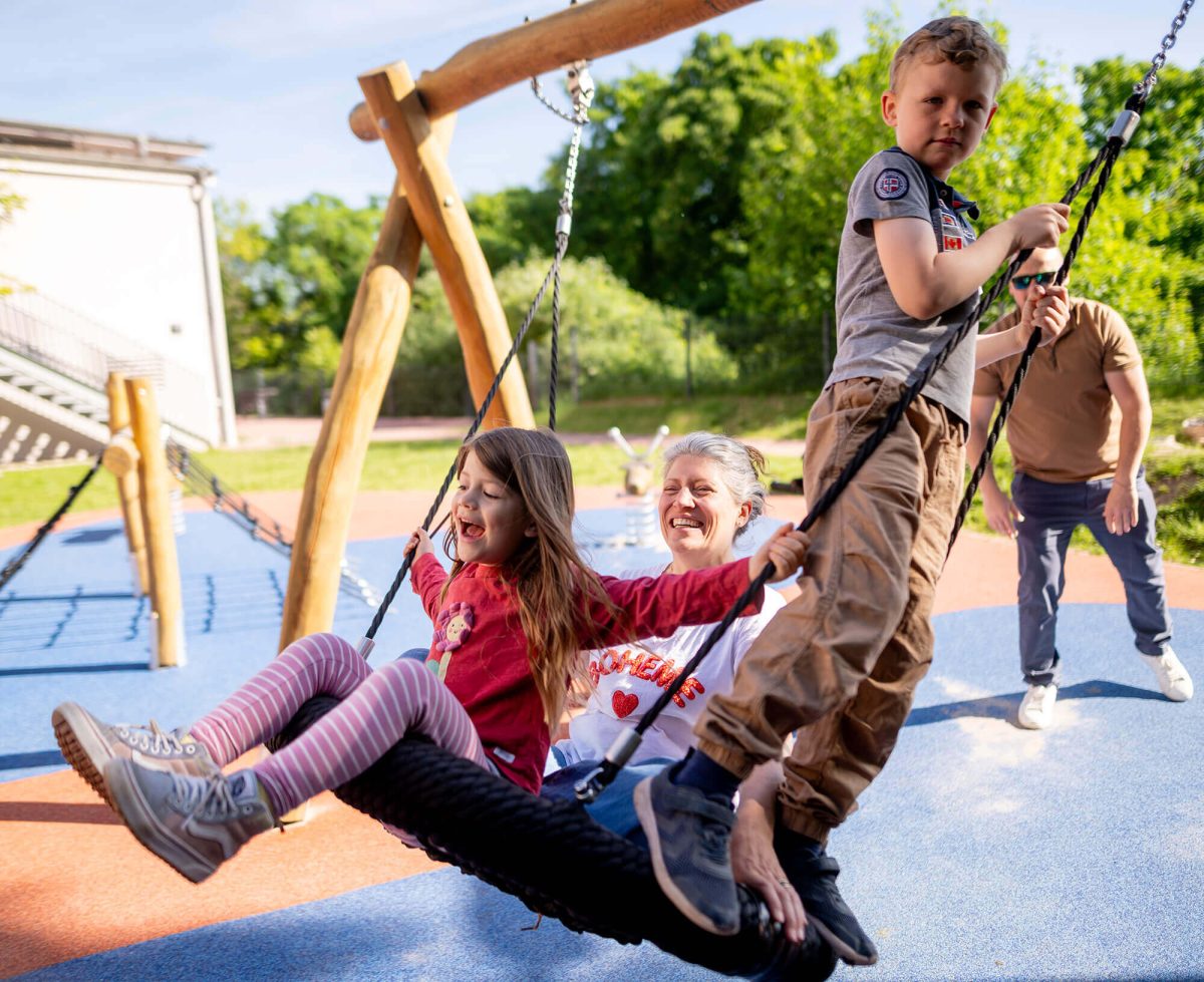 Familie schaukelt auf dem Spielplatz der Jugendherberge Mainz