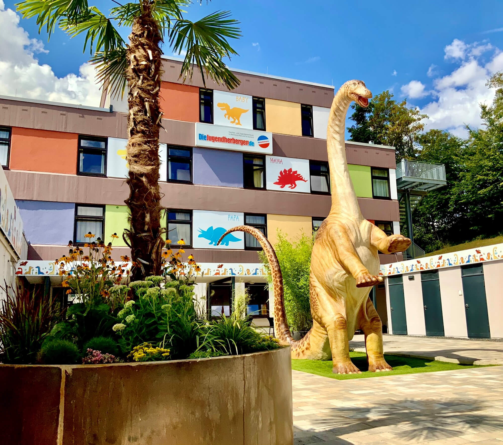 Ein großer Dinosaurier steht vor der Jugendherberge Bollendorf.