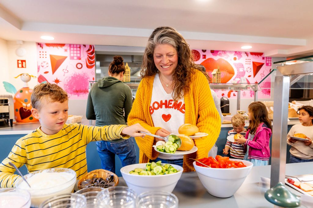 Ein Junge und eine Frau bedienen sich am reichhaltigen Salatbüfett der Jugendherberge